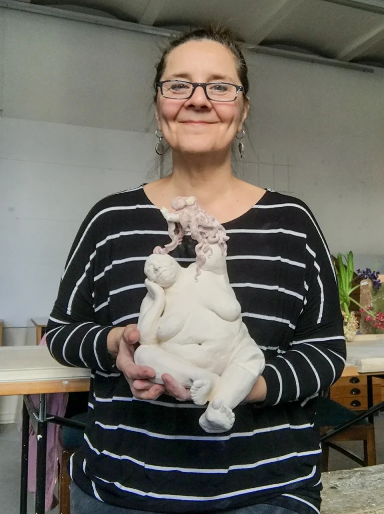 Portrait von Kea Hammann mit einer Skulptur einer Frau die einen Oktopus hält.