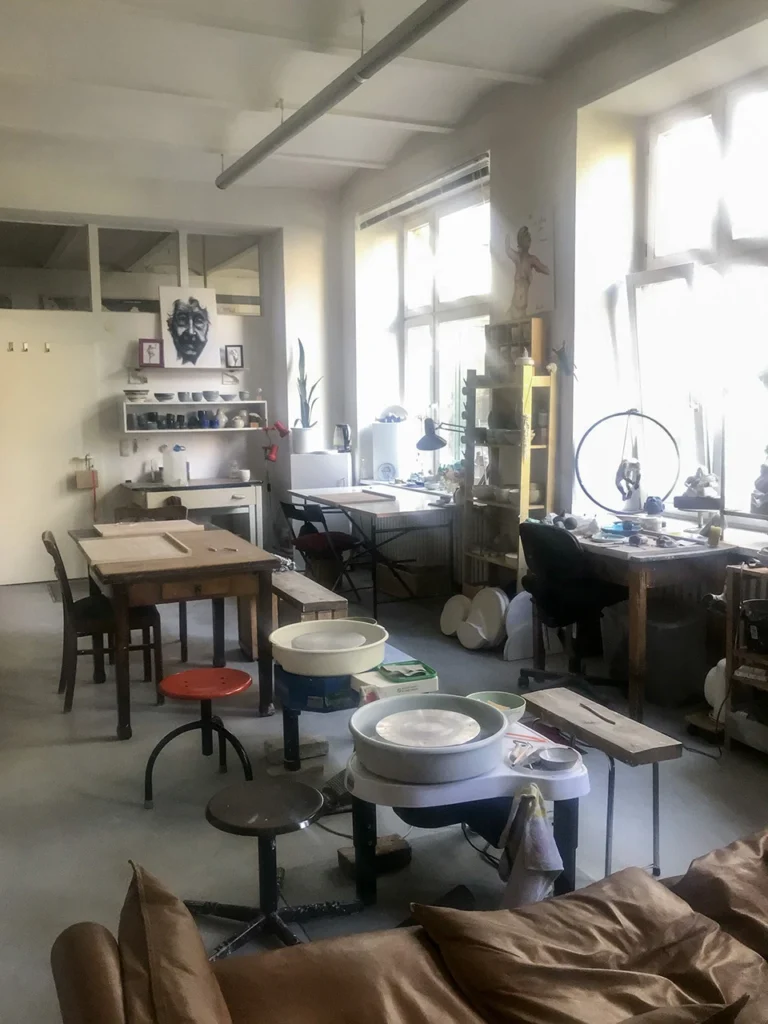 Blick ins gemütliche Atelier mit Töpfer Arbeitsplätzen und grossen Fenstern